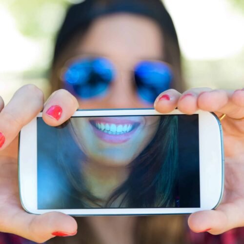 Portrait of beautiful girl taking a selfie with mobile phone in iom - instituto odontológico 5 famosos que usam aparelho